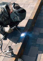 A worker works with metal welding at a construction site.