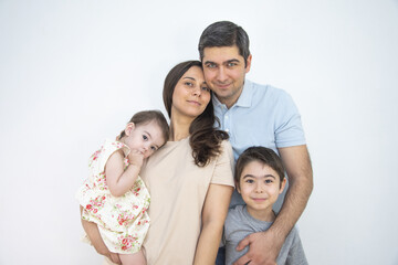 Fototapeta na wymiar Family Mom Dad Daughter and Son standing near a white wall