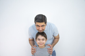 A man in a blue T-shirt stands with his son in the frame