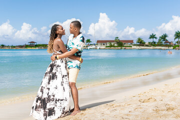 Young black couple look into each others eyes on the beach. Jamaican couple - obrazy, fototapety, plakaty