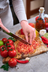 woman cutting and chopping blanched tomato by knife on wooden board