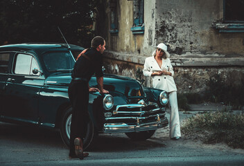 beautiful couple in retro style in suits stand near the car