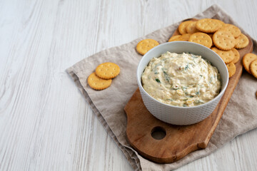 Homemade Caramelized Onion and Spinach Dip with Salty Round Crackers, side view. Space for text.