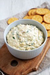 Homemade Caramelized Onion and Spinach Dip with Salty Round Crackers, side view.