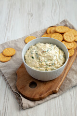 Homemade Caramelized Onion and Spinach Dip with Salty Round Crackers, side view.