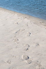 Footprints of hiking boots on the sand of a remote beach