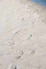 Footprints of hiking boots on the sand of a remote beach