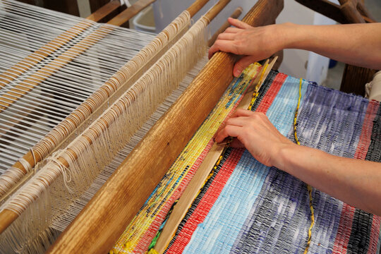 Women's hands weave a canvas on a retro loom close-up.