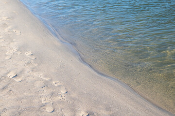 Footprints of human feet on the sand near the water on the beach