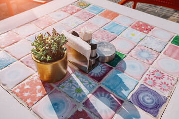 An empty table in a cafe decorated with painted tiles and a potted plant