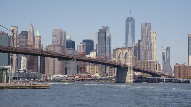 Manhattan's financial district with the One World Trade Center and the Brooklyn Bridge at a sunny day, static shot from the bankside of the East River.