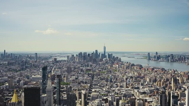 Wide panoramic view of Manhattan with the One World Trade Center and the Statue of Liberty in the distance on a sunny day, static shot.