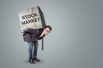 Businessman carrying a heavy stone with Stock Market written on it