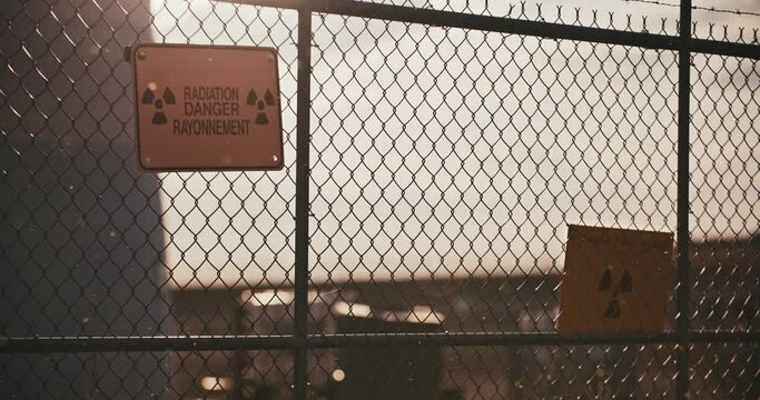 Wide Shot of Nuclear Radiation Danger Signs on Barbed Wire Perimeter Fence with Contaminated Airborne Radioactive Particles in Slow Motion 4K