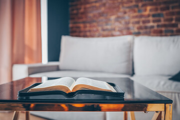 Open bible on table in living room, modern interior