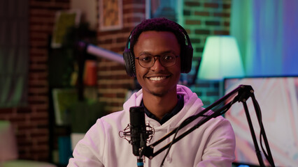 Portrait of african american podcaster smiling confident at camera while recording podcast in home...
