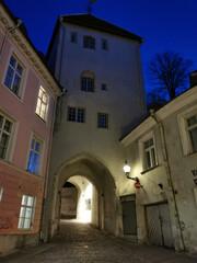 Fototapeta na wymiar An old house with a through arched passage on one of the narrow streets of Old Tallinn against the blue sky. Spring evening.