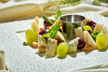 A set of different cheeses on a plate. Tough light. Selective focus. Close-up. Cheese plate