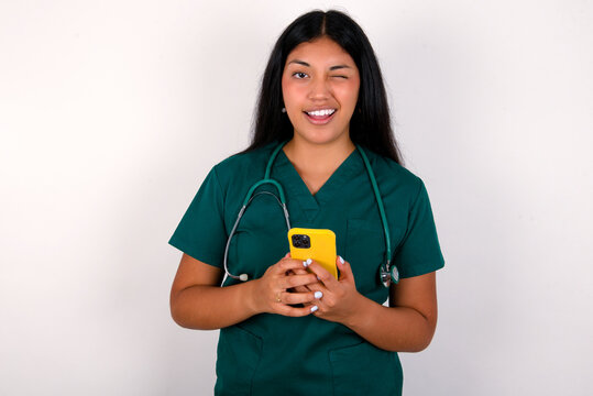 Doctor hispanic woman wearing surgeon uniform over white wall taking a selfie  celebrating success