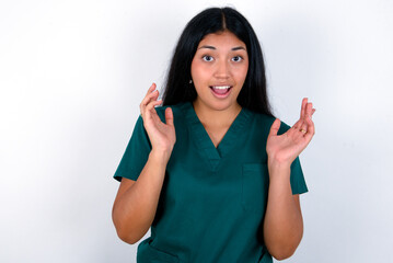 Surprised happy Doctor hispanic woman wearing surgeon uniform over white wall, glad to see big...