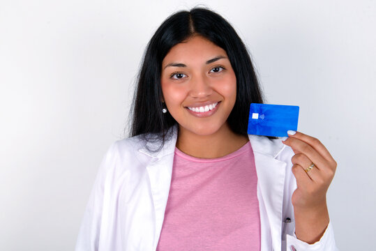 Close up photo of optimistic Young hispanic doctor girl wearing coat over white background hold card