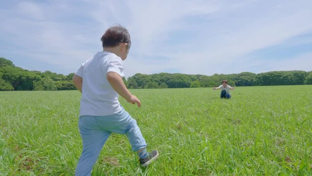草原を走る男の子と父母
