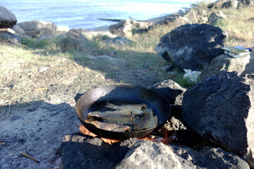 crucian carp cooked outdoors on fire in a frying pan with oil