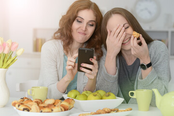 Two beautiful girlfriends talk and drink tea