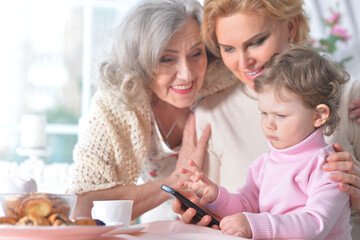 Little girl with her mother and grandmother use the phone