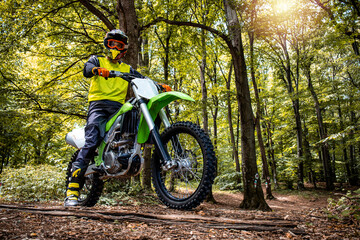 Naklejka na ściany i meble Dirt bike rider enjoying off road ride through the forest and rough terrain.