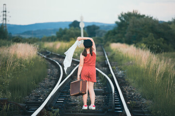 A little girl in a dress walking on an abandoned railroad tracks.