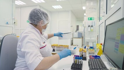 Doctor Takes Blood Sample Vial From Tray In Healthcare Laboratory. Blood Sample Scanned By Doctor With Analysis Lab Equipment. Doctor Puts Blood Sample Test Tubes Into Container. Medical Lab - Powered by Adobe