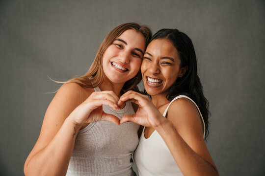 Two fun-loving girlfriends making a heart sign with there hands