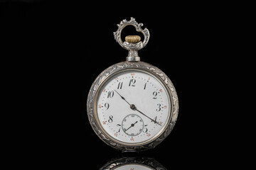 Fototapeta na wymiar Silver mechanical antique pocket watch on black isolated background. Retro pocketwatch with second, minute and hour hand. Old round clock with dial for gentleman. Vintage timepiece. Symbol of time.