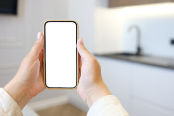Kitchen background with hand with phone. Blurred home kitchen with blank smartphone screen. Online...