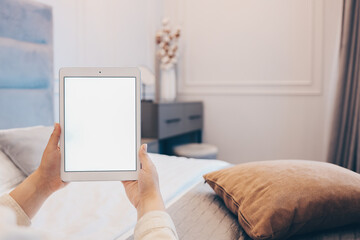 Mockup image of woman's hand holding white tablet pc with blank white screen at home