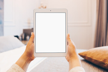 Mockup image of woman's hand holding white tablet pc with blank white screen at home