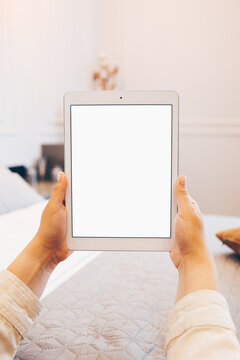 Mockup image of woman's hand holding white tablet pc with blank white screen at home