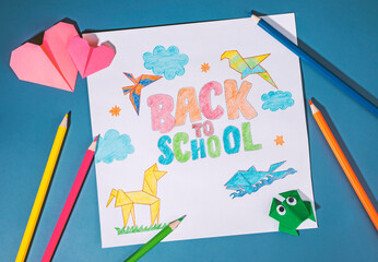 back to school children's drawing with colored pencils and origami. school supplies for back to school concept background