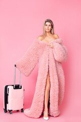 Portrait of a beautiful and young adult model of a blonde woman in a pink fashionable coat with a...