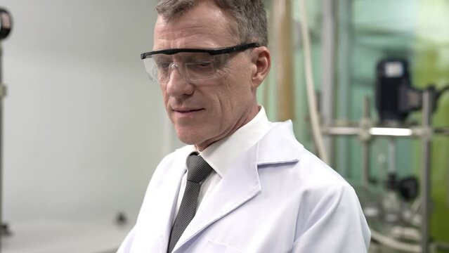 Maintenance service engineer pround smart standing holding laptop portrait in front of syphon tube canabis distillation machine 
