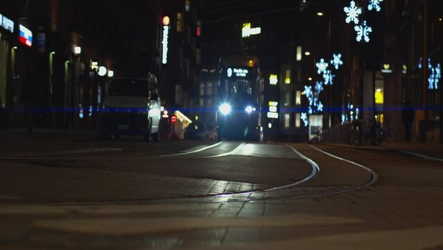 Night street trolley headlights in old world city come toward camera