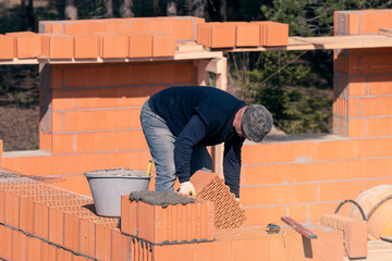 The builder lays bricks on the wall. Bricklaying. Bricklayer builder, private master. Construction of a cottage, a country house.