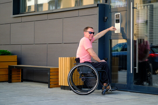 Man With Disability Who Uses A Wheelchair Dials The Access Code To The Apartment On The Door Of The House