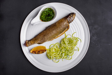 Fried salmon with lemon, sauce and parsley on a round plate and on