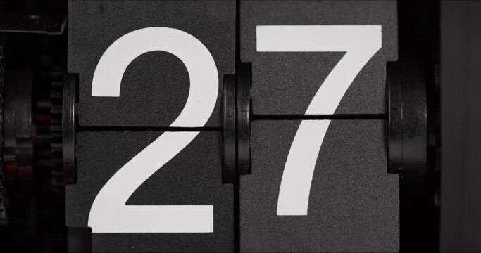 Close-up flip clock turns slowly from day 26 to 27 on black background, Time concept.