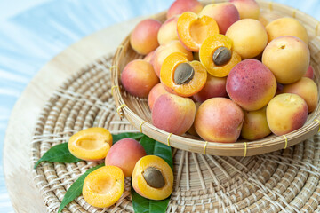 Apricot fruit with leaf on bamboo mat background, Fresh Apricot on wooden plate over wooden Background.
