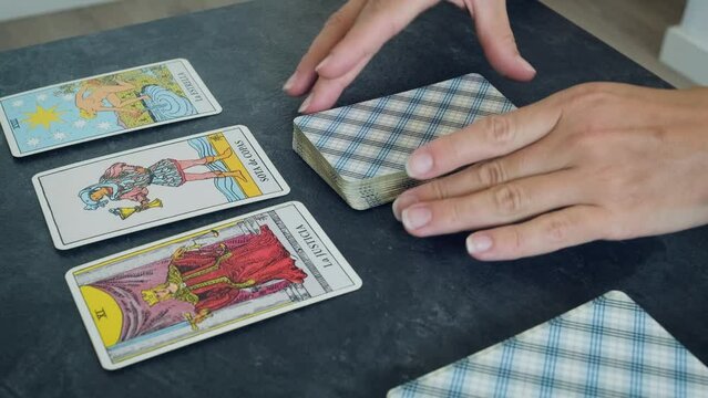women's hands shuffle a deck of tarot cards