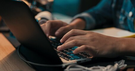Close-up of girl's hands taking notes with pencil in notebook, laptop, headphones, teenage girl has remote lessons, distance learning, online school.