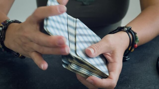 women's hands shuffle a deck of tarot cards